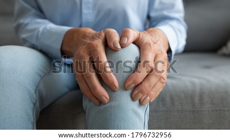 Close up mature old woman touching knee joint, having painful feelings. Unhealthy middle aged senior female retiree suffering from arthritis, bones disease osteoporosis or inflammation processes.