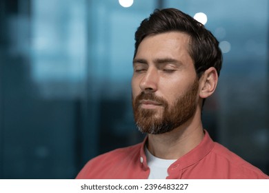 Close up of mature thinking businessman meditating and thinking with closed eyes at workplace inside office, man in red shirt resting and breathing. - Powered by Shutterstock