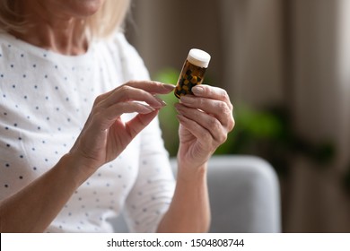 Close Up Mature Woman Holding Bottle With Pills In Hands, Reading Instruction Or Prescription On Packaging, Older Female Preparing To Take Medicine, Chronic Disease, Healthcare And Treatment Concept