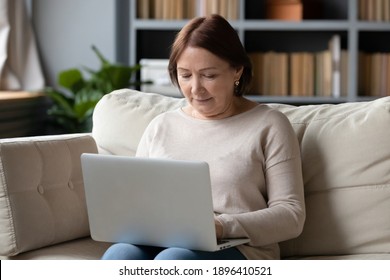 Close Up Mature Woman Using Laptop, Sitting On Couch At Home Alone, Middle Aged Female Looking At Computer Screen, Chatting Online With Relatives, Watching Video, Shopping In Internet Store