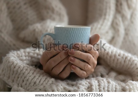 Close up mature woman wrapped warm blanket holding mug of coffee or tea, middle aged female enjoying free time, weekend at home, relaxing, drinking hot beverage in morning, starting new day