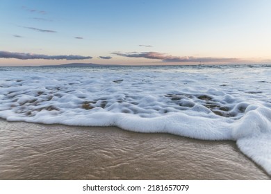 Close up of Maui Hawaii beach coastline of sand, sun, and water with crashing waves and foamy water. - Powered by Shutterstock