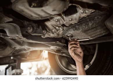 Close Up Of Mechanic Hand Change Engine Oil At Below Of A Car At The Garage. Man Examining And Maintenance Car.