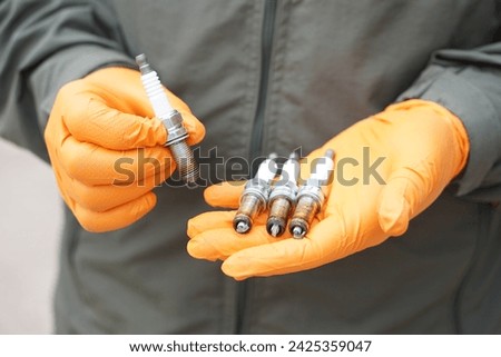 Close up mechanic hands hold old spark plug, spare part of car engine. Concept, machine maintenance, fix, repair, check or diagnose automobile problems by engine specialist.                           