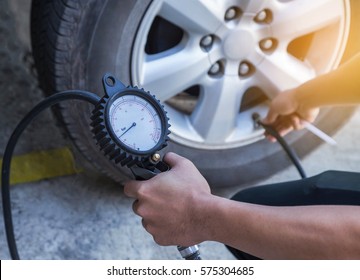 Close up mechanic inflating tire and checking air pressure with gauge pressure   