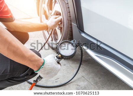 Close up mechanic inflating tire and checking air pressure with gauge pressure in service station          
