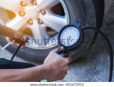 Close up mechanic inflating tire and checking air pressure with gauge pressure      