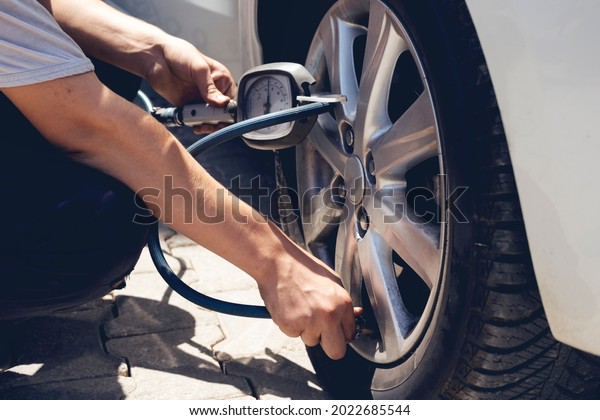 Close up\
mechanic inflating tire hand holding gauge pressure for checking\
and filling air in car tire. Automobile\
concept.