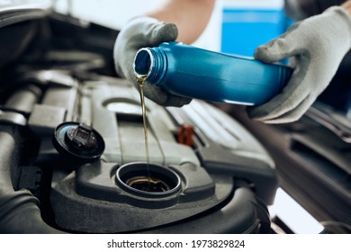 Close- Up Of Mechanic Pouring Motor Oil While Doing Car Maintenance At Auto Repair Shop. 