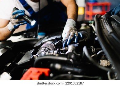 Close up mechanic working and checking engine in garage, Technician is wearing gloves and shine a flashlight on the car, Car Service and Automobile Maintenance Concept - Powered by Shutterstock