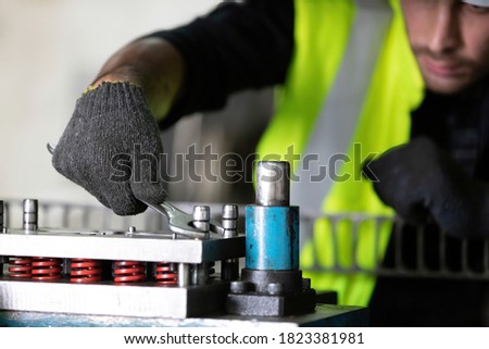 close up mechanical engineer wearing protective helmets and gloves using wrench to fix the machine