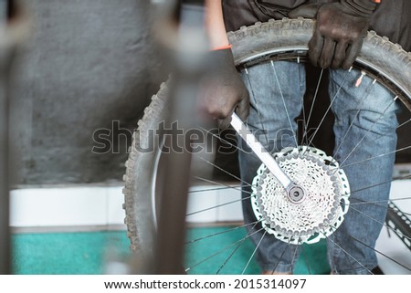 close up of a mechanic's hand in gloves locking a locknut an axle using a wrench with a workshop background
