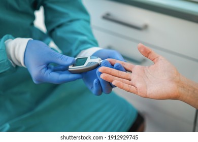 Close up of medical doctor checking blood sugar level to young patient - Focus on woman hand