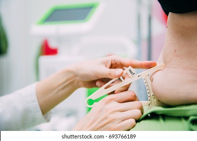 Close up of medical doctors hands measuring overweight fat woman's belly by using body fat clipper