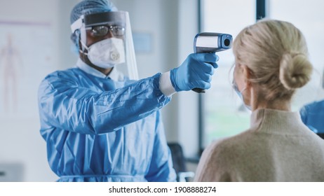Close Up of Medical Physician in Safety Gear Measuring Senior Female Patient's Body Temperature with Infrared Thermomether in a Health Clinic. Doctor Uses Touch-free Technology to Diagnose Symptoms. - Shutterstock ID 1908888274