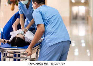 Close Up Medical Team Do CPR To Seriously Injured Patient With Oxygen Mask While Push Gurney Stretcher Bed To Operating Room. Emergency Health Care And Medical Hospital Concept.