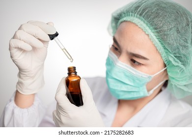 Close Up Medical Technologist Asian Woman Looks At A Bottle Of CBD Oil. Research On Cannabis Extracts. Sleep Supplement. Medical Marijuana. Vitamins And Supplements Healthy Alternatives.
