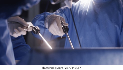 Close up of medics using laparoscopy instruments during surgery. Professional surgeons in surgical suits perform difficult operation using modern equipment. Medical staff save life in medical center.