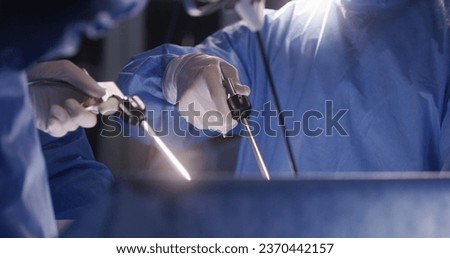 Close up of medics using laparoscopy instruments during surgery. Professional surgeons in surgical suits perform difficult operation using modern equipment. Medical staff save life in medical center.