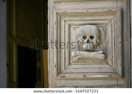 Close up of the medieval wooden door with skull and crossbones carved into it at the entrance to the Church of the Purgatory in Matera, Italy.