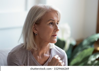 Close up melancholic 60s elderly woman looks away face lit by sunlight when feels hurt and lonely, pensive old female lost on sad thoughts, aging process, go through divorce personal problems concept