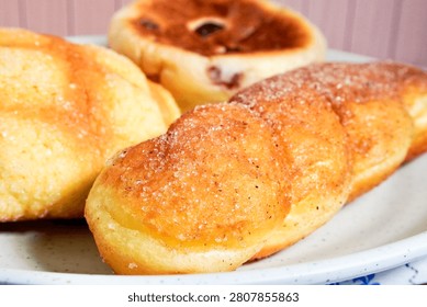 Close up melon pan bread, raspberry cheese bread, and cinnamon sugar coated bread on white plate.