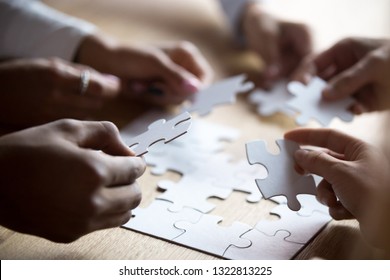 Close Up Members Of Multiracial Team Assembling White Puzzle, African American And Caucasian People Searching Solution Together, Team Building Activity, Staff Training, Support And Unity