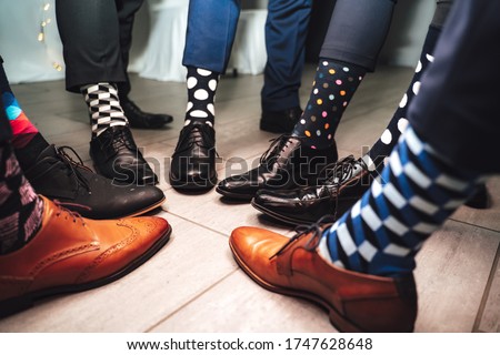 Close up of men legs wearing formal shoes and funny colorful socks. Seven friends feet in circle composition.