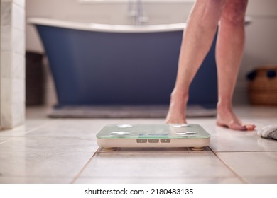 Close Up Of Menopausal Mature Woman Concerned With Weight Gain Standing On Scales In Bathroom