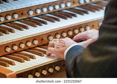 Close- up of a men's hands playing a three-manual church organ. Musical education concept.