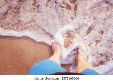 close up of a men's legs stand on the beach covered by soft sea wave form, travel and summer vacation concept. - Shutterstock ID 1371368606