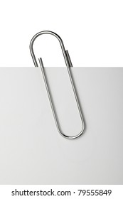 close up of  a metal paper clip and paper on white background