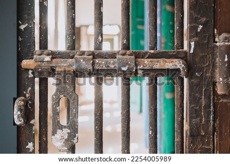 Close up of metallic door latches cage before access area, rusty entrance fence - Safety and protection concept