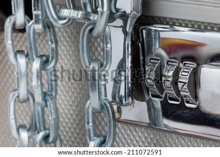 Close up of metallic suitcase with safety code and chains around it