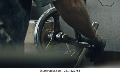 Close up of a metalworker's hands skillfully operating a lathe machine, turning and shaping metal components in a workshop environment, showcasing precision and craftsmanship in metal production