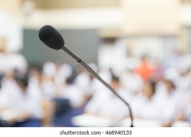 Close up Microphone selective focus over the blurred photo of conference hall or seminar room background.