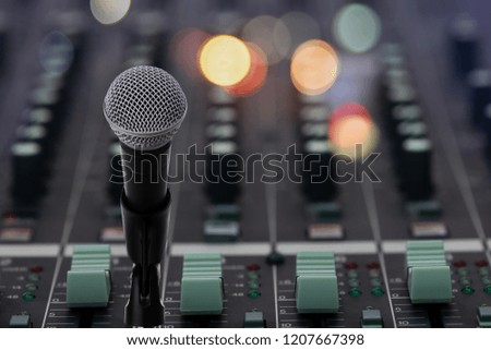 Close up of microphone  setting on stand in front of audio mixing board with colorful light bokeh ,showbiz concept.
Microphone in recording studio.