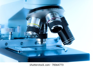 Close up of microscope lenses focused on a specimen in blue light. - Powered by Shutterstock
