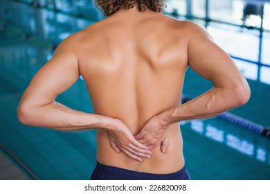 Close up mid section of a shirtless fit swimmer with back ache by the pool - Powered by Shutterstock