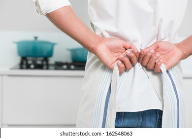 Close up mid section of a young man wearing apron in the kitchen - Powered by Shutterstock