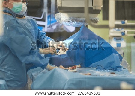 Close up of middle aged surgeon performing minimally invasive procedure in operating room using imaging equipment. Ideal for healthcare technology, surgery, hospital care marketing