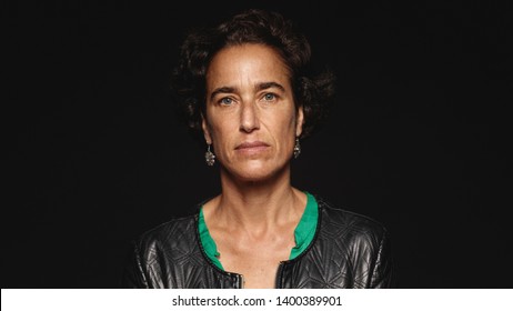 Close Up Of A Middle Aged Woman With Short Hair Isolated On Black Background. Portrait Of A Woman Looking At Camera.