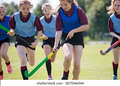 Close up of Middle schoolgirls playing hockey on the field in physical education class - Powered by Shutterstock