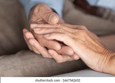 Close up of middle-aged 60s husband and wife hold hands show support and care, loving mature elderly couple embrace cuddle sharing having tender close romantic moment at home, relationships concept