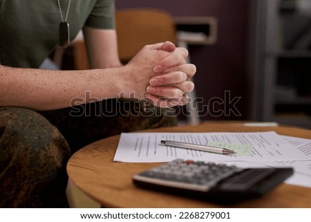 Close up of military woman working on financial documents with hands clasped, copy space