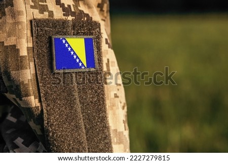 Close up millitary woman or man shoulder arm sleeve with Bosnia and Herzegovina flag patch. Bosnia and Herzegovina troops army, soldier camouflage uniform. Armed Forces, empty copy space for text
