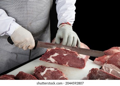 Close up of minced meat pieces and butcher's male hands in special gloves cutting with knife. Meat pork or beef on the butcher's table. Worker in white uniform and special steel apron. - Powered by Shutterstock