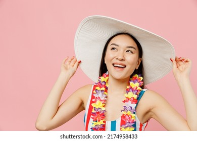 Close Up Minded Happy Fun Young Woman Of Asian Ethnicity Wear Swimsuit Hawaii Lei White Hat Look Aside On Workspace Isolated On Plain Pastel Pink Background. Summer Vacation Sea Rest Sun Tan Concept.