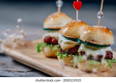 Close up of mini burgers with cheese, onion, lettuce salad and cucumber. Fast food concept - Powered by Shutterstock