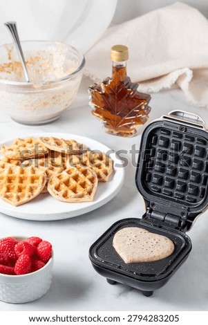 A close up of a mini waffle maker with batter to make heart waffles. Stock photo © 